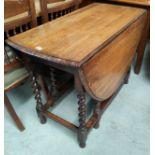 A 1930's oak dining table with oval drop leaf top on barley twist gate legs
