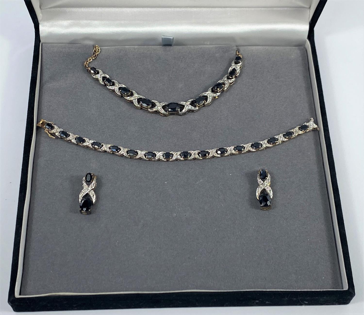 A silver gilt suite comprising necklace, bracelet and earrings, set dark blue and clear stones,