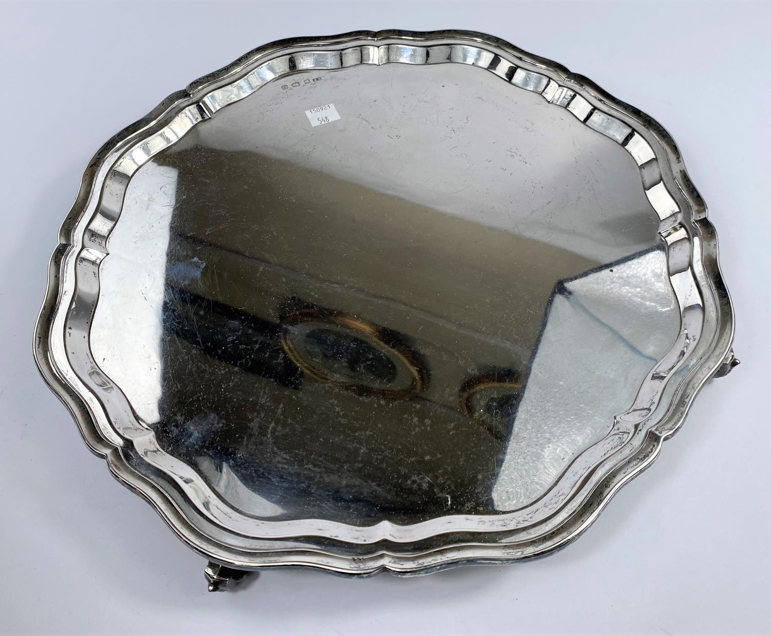 A hallmarked silver circular salver with wavy rim, on circular scroll feet, Sheffield 1951, diameter