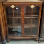 A reproduction walnut display cabinet enclosed by 2 glazed doors