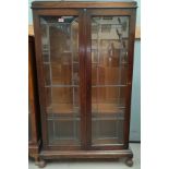 A 1930's oak display cabinet enclosed by 2 leaded glass doors