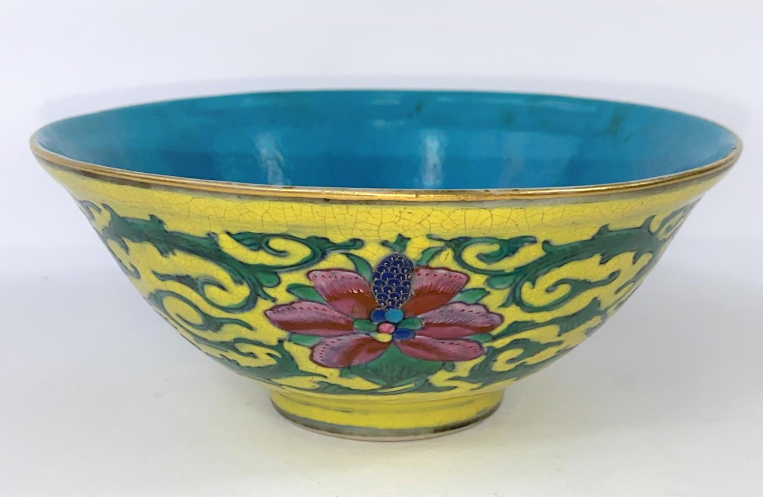 A Chinese yellow glaze bowl with detailed leaves connecting three red flowers, with turquoise