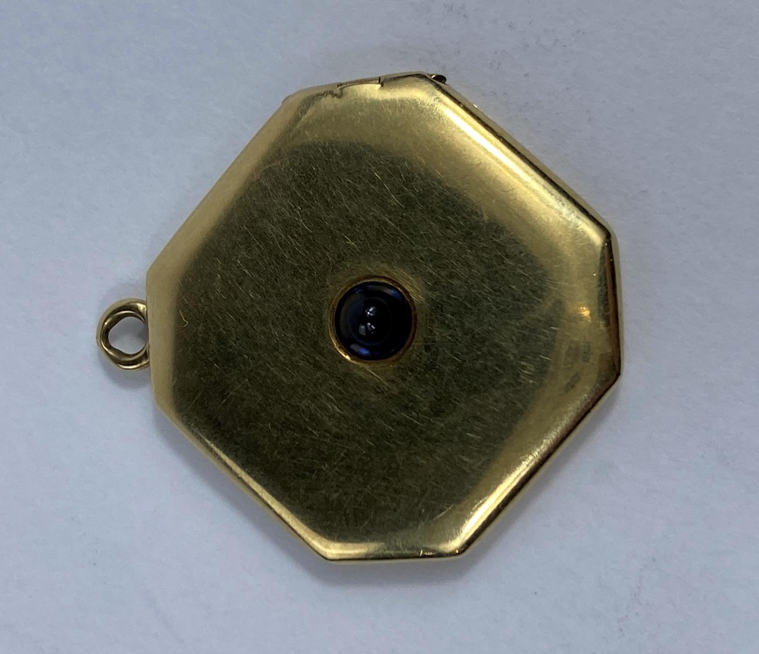 A yellow metal octagonal locket set cabochon cut blue coloured stone, unmarked, 7.8 gm (tests over