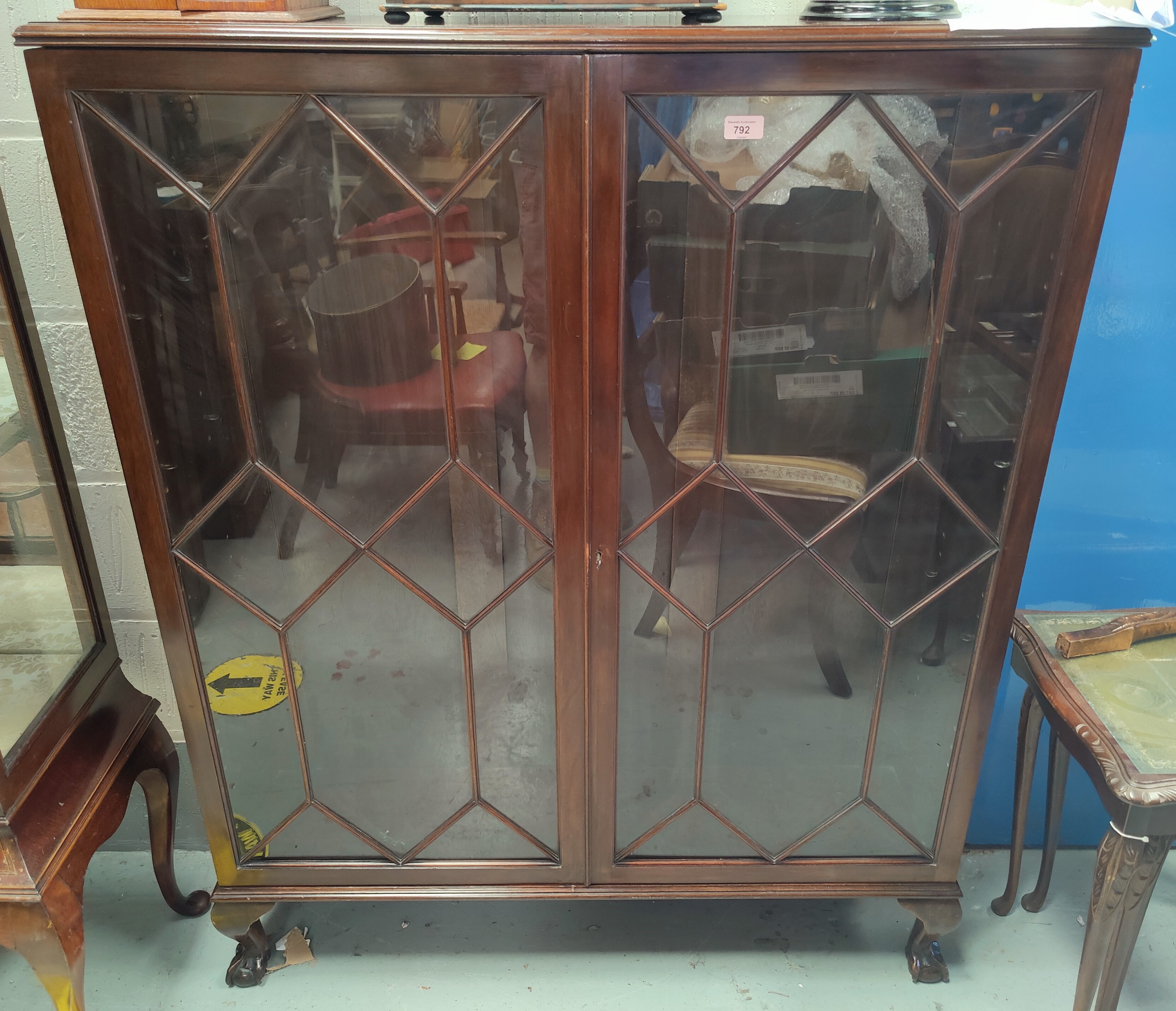 An early 20th century mahogany display cabinet enclosed by 2 astragal glazed doors, on ball and claw
