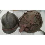 A steel battle helmet with camouflage webbing and a French WWI style helmet