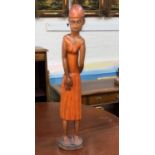 A tall carved wooden figure of a female in dress with a head scarf, height 75cm
