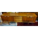 A mid 20th century teak long low side board with double cupboards to both ends and four central