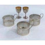 A set of 3 continental white metal glass holders, 6oz., a pair of miniature Far Eastern dwarf