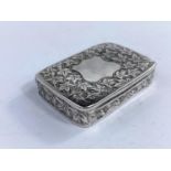 A rectangular silver snuff/pill box with chased leaf decoration and shield cartouche, hinged lid,