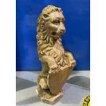A reconstituted stone garden ornament in the form of a heraldic seated lion holding a shield, in