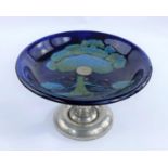 A Moorcroft Moonlit Blue pattern cake dish on a Tudric pewter pedestal stand.