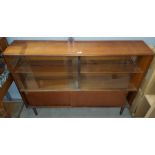 A mid 20th century teak bookcase with two sliding glass doors above and sliding solid doors below on