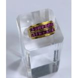 A yellow metal dress ring stamped 22ct set with two rows of square cut rubies in a double split