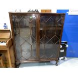 An early 20th century mahogany display cabinet enclosed by 2 astragal glazed doors, on ball and claw