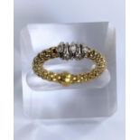 A woven yellow metal ring stamped "750" with 5 small diamonds on circular white metal loops, 3.