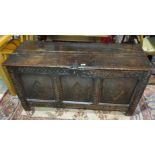 A late 18th/19th century oak panneled chest with hinged plank top lid with carved decoration to