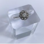 An 18 carat white gold dress ring with central diamond surrounded by 8 smaller diamonds in