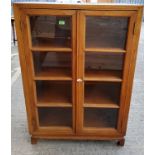 A Chinese stripped wooden display cabinet/bookcase with glazed doors and arched feet