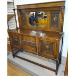 A 1920's oak mirror back sideboard with two carved doors and drawers below with canted rectangular