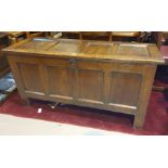 An 18th century framed and panelled oak blanket box with hinged lid and black feet.