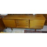 A mid century long low teak sideboard with four central drawers and side cupboards and an extending