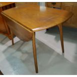 An Ercol style light oak drop leaf circular dining table on tapering legs, diameter 112cm and height