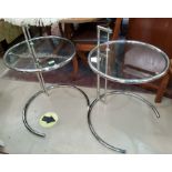 A pair of desinger Eileen Gray style adjustable side tables in stainless steel with circular glass