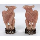 A 20th century Chinese pair of carved rose quartz figures of mythical birds, on hardwood bases,