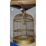 An antique style brass bird cage with wooden hanger