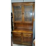 An Ercol medium oak wall unit with double glazed over 2 linen fold doors and 2 drawers