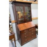 A Georgian bureau bookcase with glazed double doors to the top with arched decoration, four