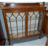 A 1920's mahagany display cabinet, enclosed by two astrgal glazed doors on ball and claw feet