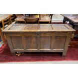 An 18th century framed and panelled oak blanket box with hinged lid and black feet.
