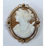 A shell cameo, female bust portrait, in yellow metal rope twist and wirework surround, stamped '9