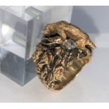 A yellow metal dress ring in the form of a mountain cat climbing rocks, stamped 14k with two