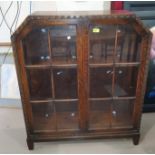 A 1930's oak display cabinet enclosed by 2 glazed doors