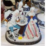 A Dresden style china two bottle ink stand, the cover in the form of figures playing chess, length