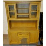 A modern light oak dresser with 3 central drawers, two cupboards below, two glass doors above with