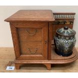 A late Victorian oak smokers cabinet enclosed by a bevel glazed door, with a Doulton Lambeth tobacco