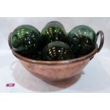 A 16' copper bowl with a collection of ten green glass witch balls