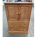 A pine cupboard, enclosed by a pair of panel doors over three long drawers on plinth support. 30'