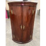 A George III mahogany bowfronted hanging corner cupboard. 44½' high