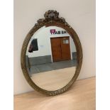 A gilt framed oval looking glass with bevelled plate. 23½' high