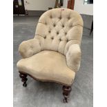 A Victorian upholstered lady's chair with deep buttoned back and arms, on turned legs