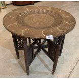 A Benares tray top table on fret and blind carved folding base. 23' diam