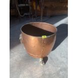 A copper coal bucket on brass paw feet