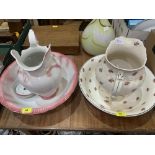 Two washstand jug and bowl sets, the pink jug cracked