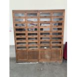 A pair of haberdashery cupboards, each with sixteen glazed drawers over a base cupboard enclosed