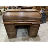 An early 20th century oak roll-top desk enclosed by a tambour shutter. 47' wide
