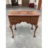 An antique walnut lowboy, the quarter veneered crossbanded top over three banded drawers and